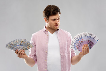 Image showing uncertainy man with fans of euro and dollar money