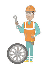 Image showing Young hispanic mechanic with tyre and spanner.