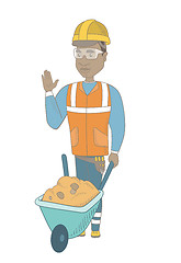 Image showing Young african builder standing near wheelbarrow.