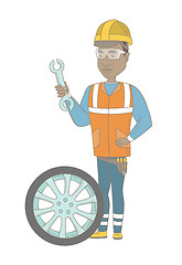 Image showing Young african mechanic with tyre and spanner.