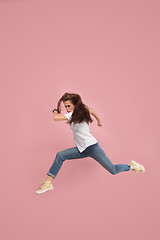 Image showing Freedom in moving. Pretty young woman jumping against pink background