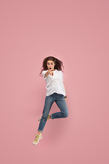 Image showing Freedom in moving. Pretty young woman jumping against pink background