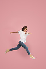 Image showing Freedom in moving. Pretty young woman jumping against pink background