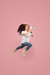 Image showing Beautiful young woman jumping with megaphone isolated over pink background