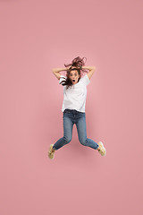 Image showing Freedom in moving. Pretty young woman jumping against pink background