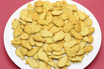 Image showing Fish-shaped cookies in a white plate on a crimson background 