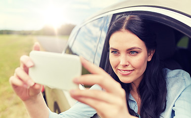 Image showing happy young woman driving in car with smartphone