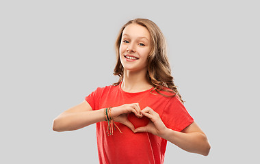 Image showing smiling teenage girl in red making hand heart