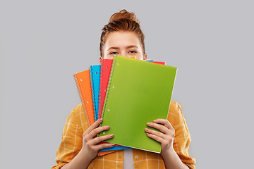 Image showing teenage student girl hiding behind notebooks