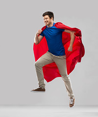 Image showing man in red superhero cape jumping in air