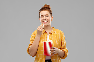 Image showing smiling red haired teenage girl eating popcorn