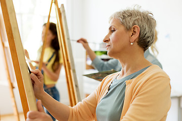 Image showing senior woman drawing on easel at art school studio