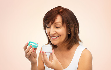 Image showing smiling senior woman with cream jar