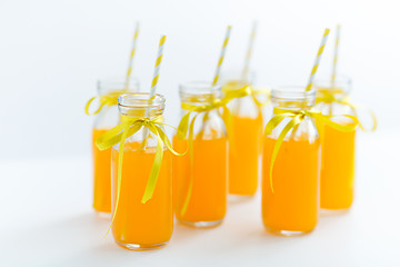 Image showing orange juice in glass bottles with paper straws