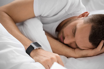 Image showing close up of man with smart watch sleeping in bed