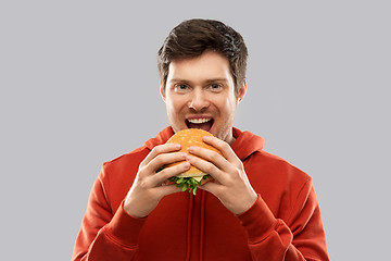 Image showing happy young man eating hamburger