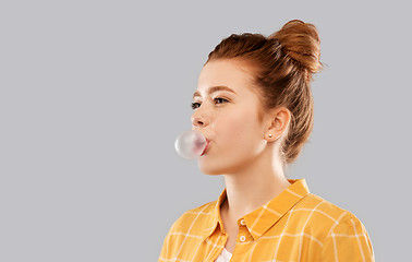 Image showing red haired teenage girl blowing bubble gum