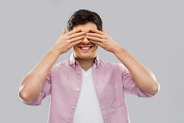 Image showing man closing his eyes by hands over grey background