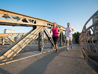 Image showing young couple jogging across the bridge in the city