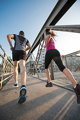 Image showing young couple jogging across the bridge in the city