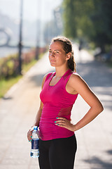 Image showing woman drinking water from a bottle after jogging