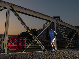 Image showing man jogging across the bridge in the city