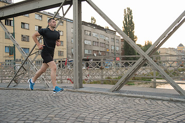 Image showing man jogging across the bridge at sunny morning