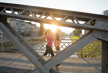 Image showing young couple jogging across the bridge in the city