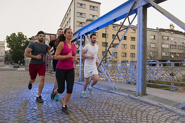 Image showing group of young people jogging across the bridge