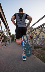 Image showing man jogging across the bridge at sunny morning