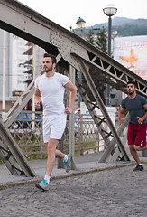 Image showing group of young people jogging across the bridge