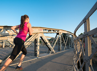 Image showing woman jogging across the bridge at sunny morning