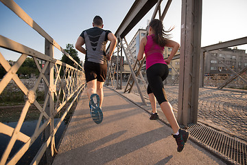 Image showing young couple jogging across the bridge in the city