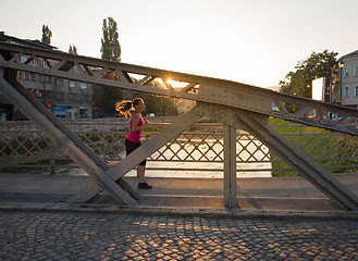 Image showing woman jogging across the bridge at sunny morning