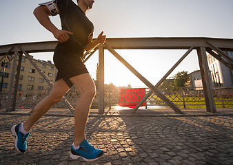 Image showing man jogging across the bridge at sunny morning