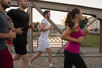 Image showing group of young people jogging across the bridge