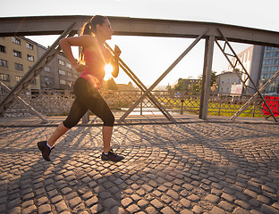 Image showing woman jogging across the bridge at sunny morning