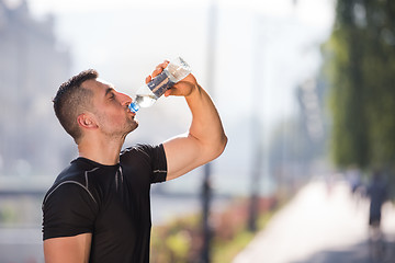 Image showing man drinking water from a bottle after jogging