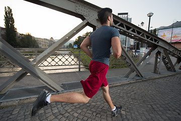 Image showing man jogging across the bridge at sunny morning
