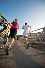 Image showing young couple jogging across the bridge in the city