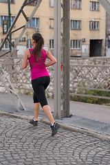 Image showing woman jogging across the bridge at sunny morning