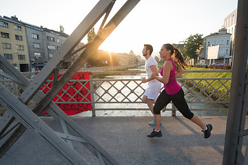 Image showing young couple jogging across the bridge in the city