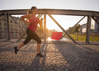 Image showing woman jogging across the bridge at sunny morning