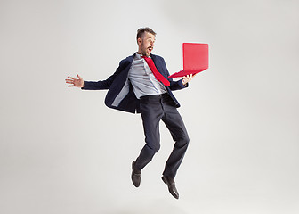 Image showing Image of young man over white background using laptop computer while jumping.