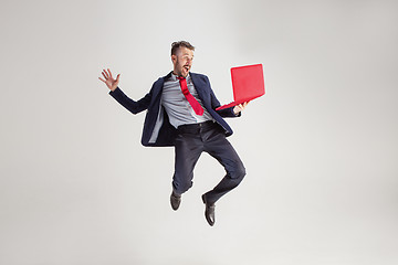 Image showing Image of young man over white background using laptop computer while jumping.