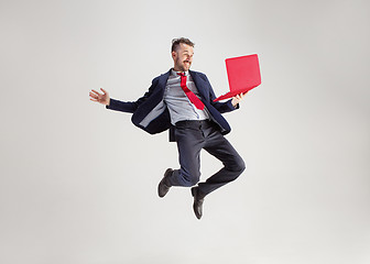 Image showing Image of young man over white background using laptop computer while jumping.