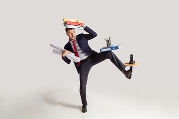 Image showing Young businessman in a suit juggling with office supplies in his office, isolated on white background