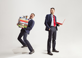 Image showing Young businessman in a suit juggling with office supplies in his office, isolated on white background