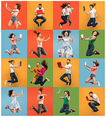 Image showing Image of young women and man over colorful background using laptop computer or tablet gadget while jumping.