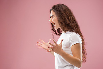 Image showing The young emotional angry woman screaming on pink studio background